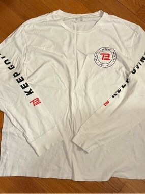 TB12 White Long Sleeve Shirt with Black "KEEP GOING" Text and Red Logo